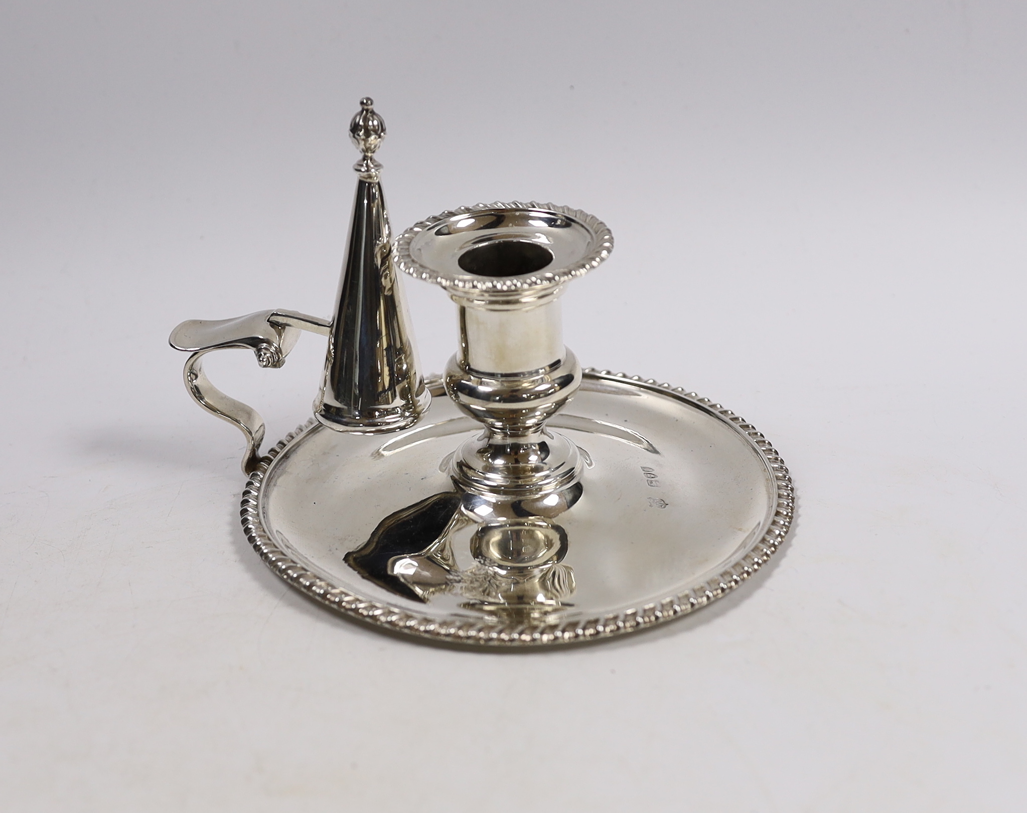 A late Victorian silver chamberstick and matching extinguisher, by Goldsmiths & Silversmiths, London, 1895, with gadrooned border, base diameter 15cm, 9.7oz.